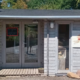 Kleiner Hofladen in einer Holzhütte mit großen Fenstern und einem großen dekorativen Ei vor dem Eingang.